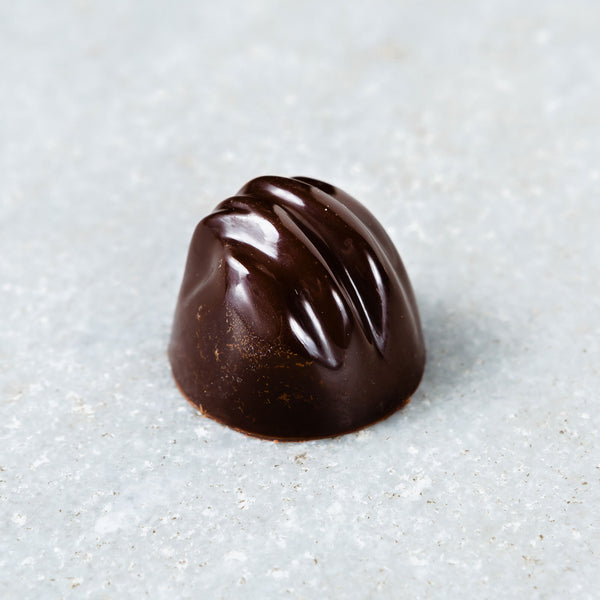 Tempered sea salt caramel dark chocolate truffle accented with gold specks.